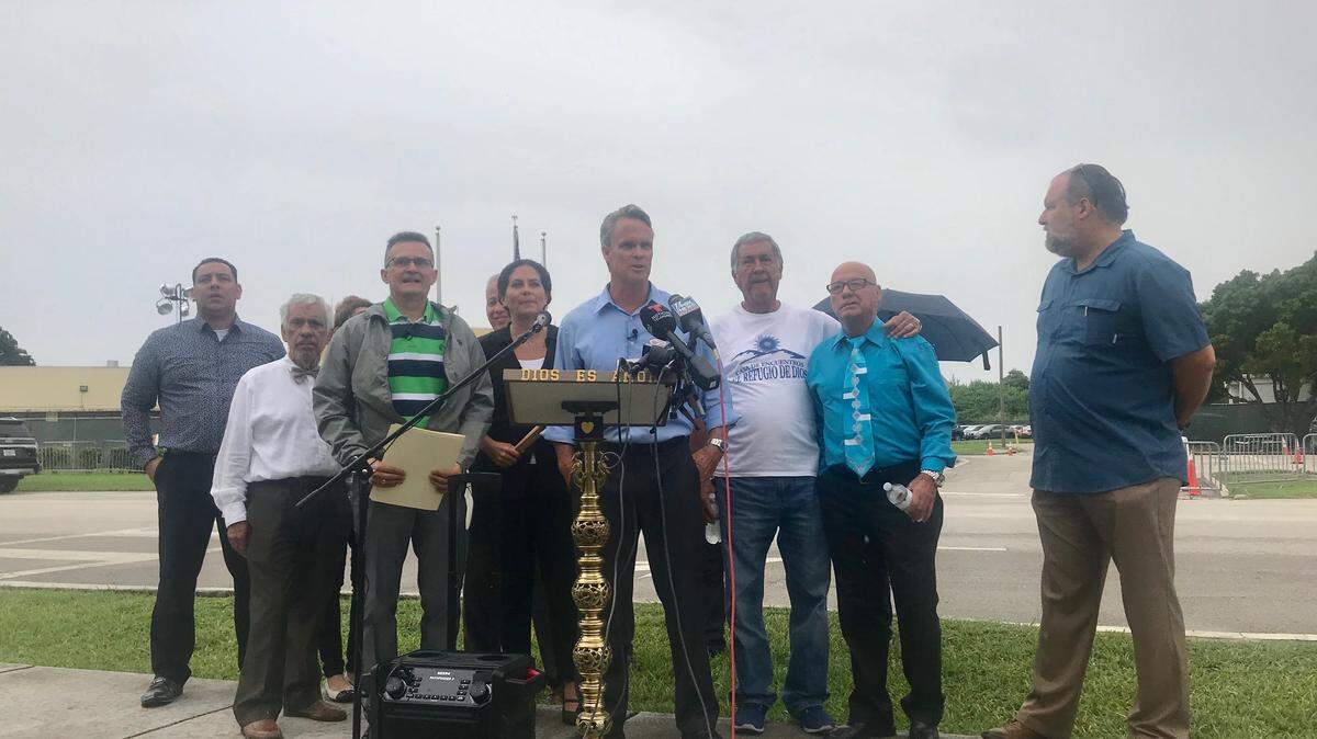 South Dade pastor Russell Black  (center) is accompanied by various area ministers and religious volunteers. The group help a news conference outside the Homestead detention center Friday.