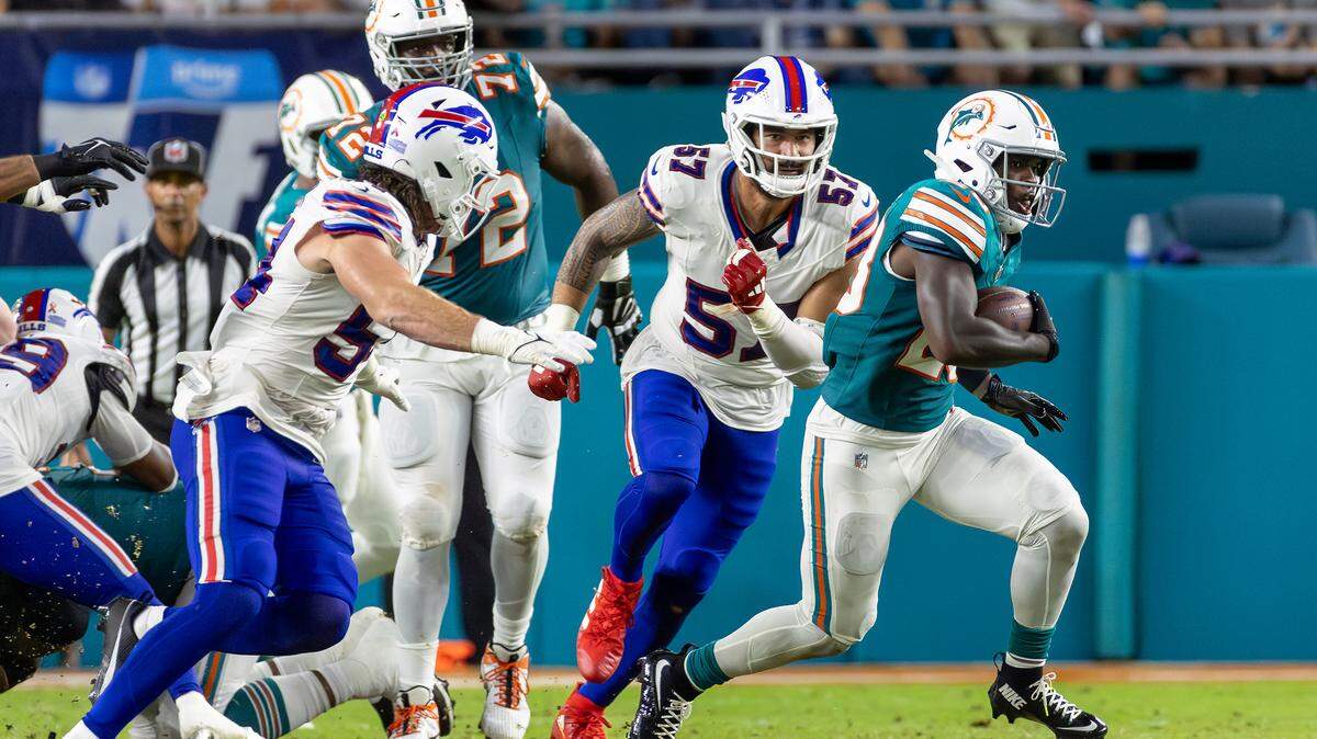 Miami Dolphins running back De’Von Achane (28) runs as Buffalo Bills defensive end AJ Epenesa (57) defends with the football in the first half of their NFL game against the Buffalo Bills at Hard Rock Stadium on Thursday, Sept. 12, 2024, in Miami Gardens, Fla.