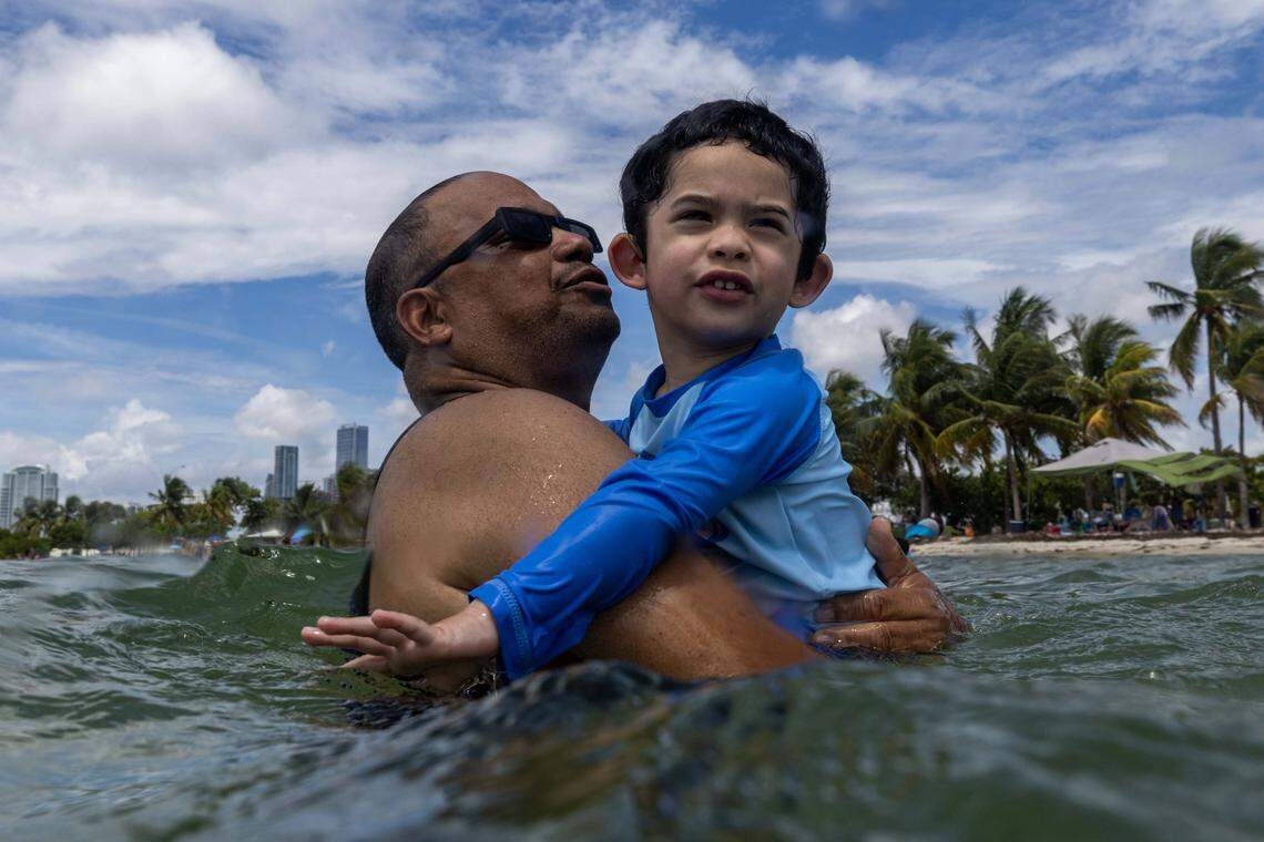 Kentucky natives Javier and his son Matthew, 3, hang in the shallows as Matthew is introduced to the beach for the first time ever while vacationing at Hobie Island Beach on Monday, September 1, 2025, in Key Biscayne, Fla. 