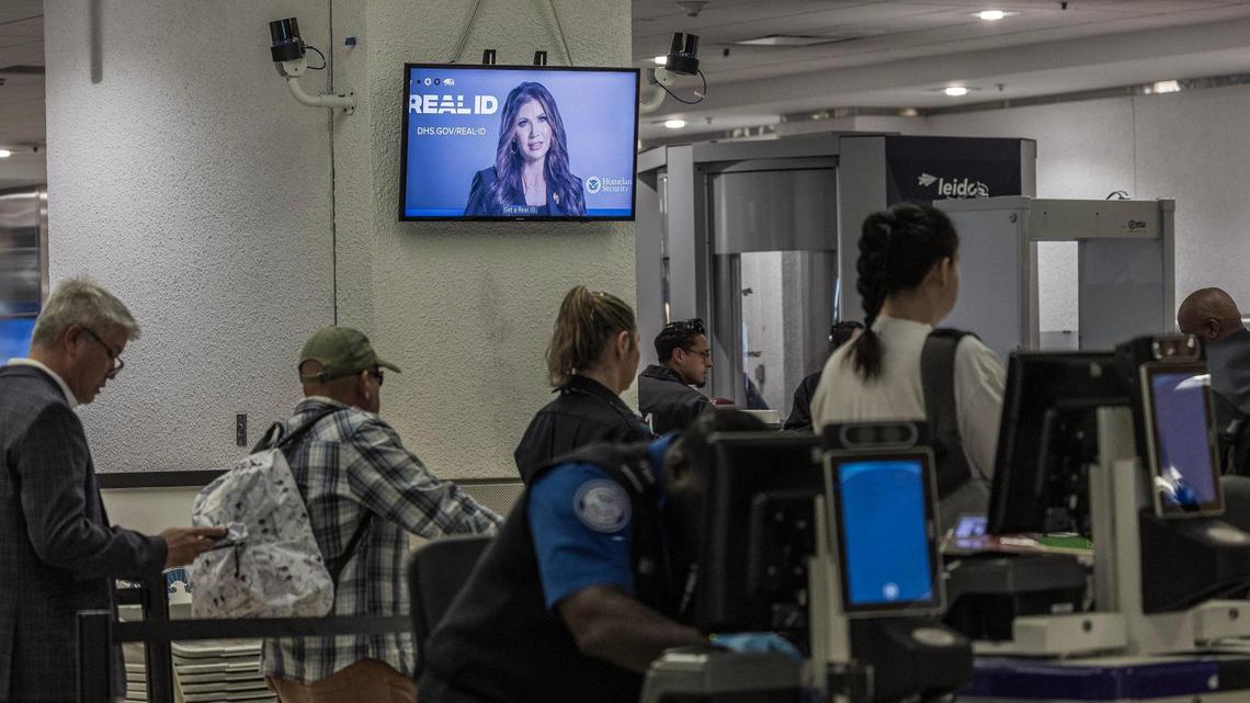 Passengers go through a checkpoint as information about REAL ID plays on a screen at Miami International Airport on Wednesday, May 7, 2025.