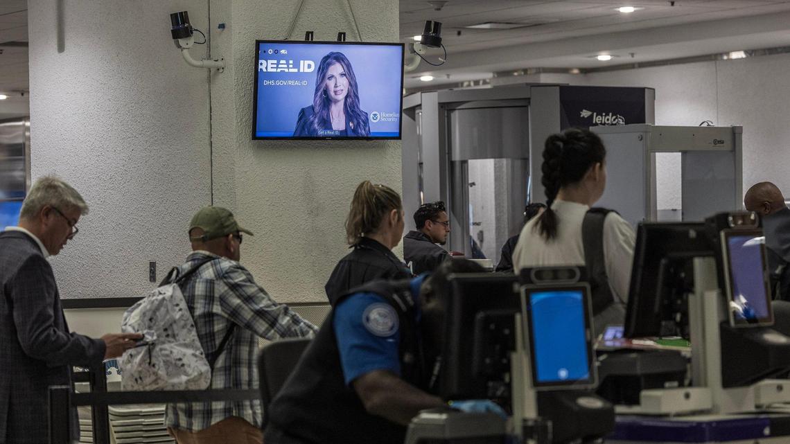 Passengers go through a checkpoint as information about REAL ID plays on a screen at Miami International Airport  on Wednesday, May 7, 2025.