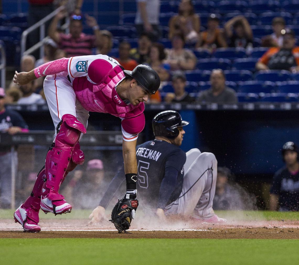 Atlanta Braves first baseman Freddie Freeman slides safely into home plate to scores as Miami Marlins catcher J.T. Realmuto misses the tag during the first inning of a baseball game at Marlins Park on Sunday, May 13, 2018, in Miami, FL.