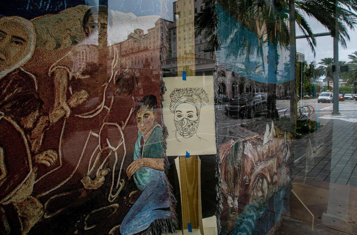 Coral Gables, Florida, Nov. 25, 2020: The streetscape is reflected in the window of a shop where textiles by Aida Tejada are on display along Miracle Mile. One property owner, Terranova, is letting artists use several vacant shops as studios and galleries through the end of the year.