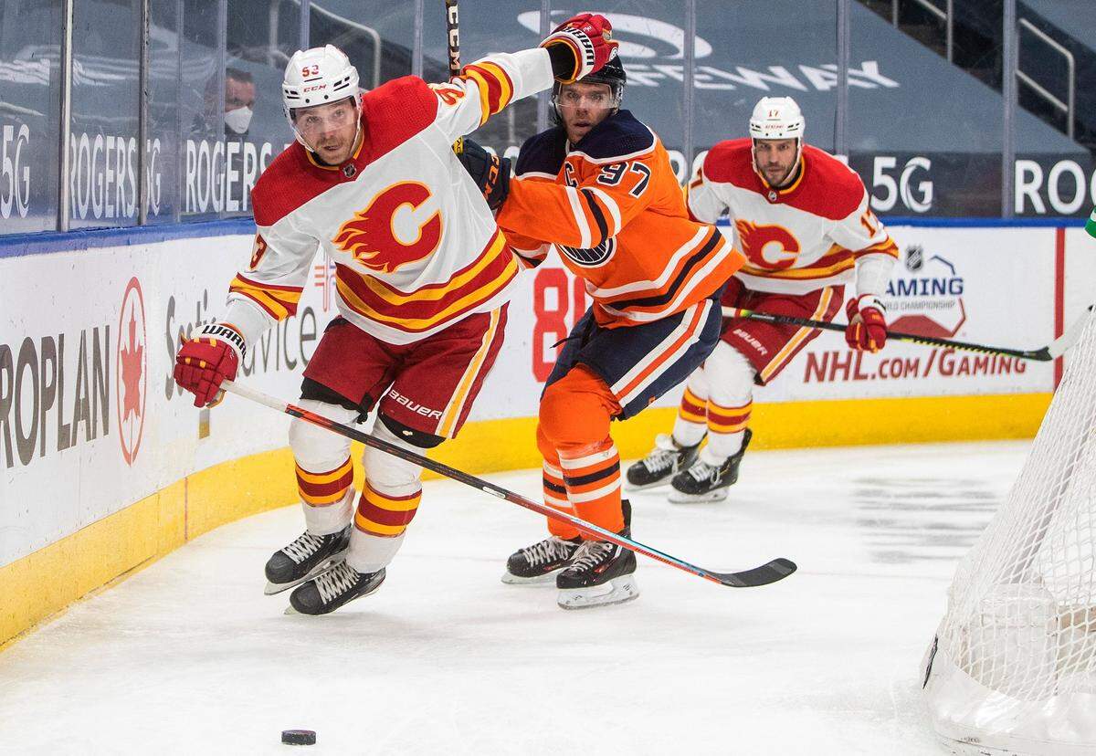 Edmonton Oilers’ Connor McDavid (97) and Calgary Flames’ Sam Bennett (93) vie for the puck during the third period of an NHL hockey game Friday, April 2, 2021, in Edmonton, Alberta. (Jason Franson/The Canadian Press via AP)