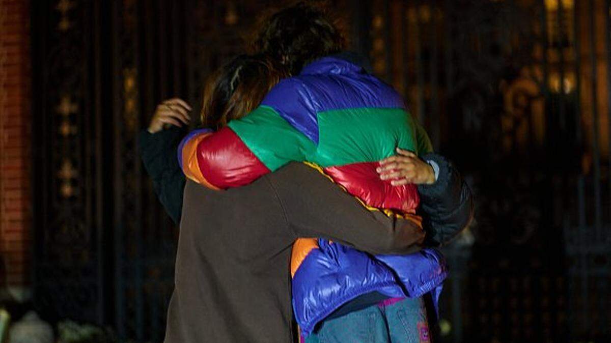 Brown University students embrace at a makeshift memorial for victims of a December 13 mass shooting that killed two and wounded at the Van Winkle Gates outside Brown's college campus in Providence, Rhode Island, on December 15, 2025. A gunman remained at large after a weekend mass shooting at elite Brown University left two dead and nine wounded, with US authorities releasing new footage of a masked "person of interest" captured on surveillance cameras. The shooting took place December 13 in a building where exams were underway on the Ivy League campus in Providence, Rhode Island when a man with a rifle burst in and opened fire before fleeing. (Photo by Bing Guan / AFP via Getty Images)