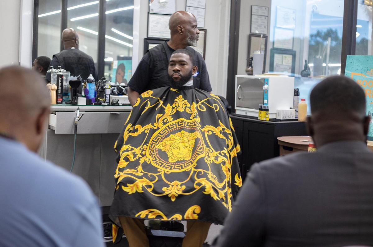 Barber Michael Stephens cuts Jefferson Noel’s hair at Topcuttaz barbershop in Miami Gardens.