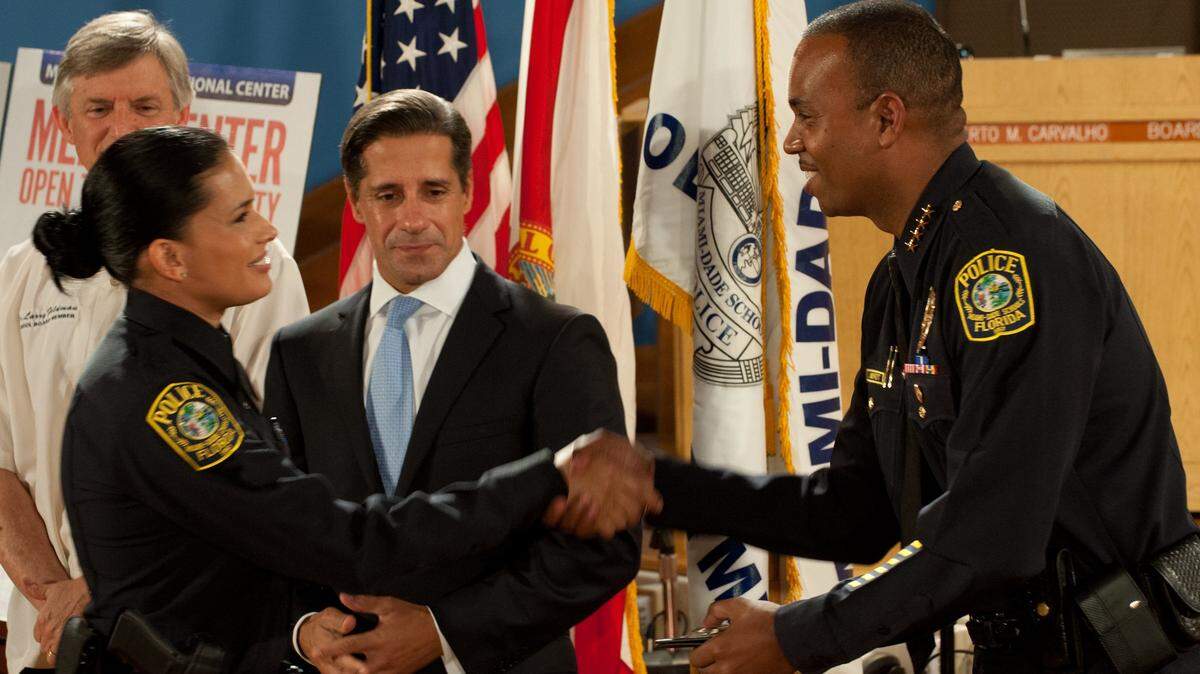 Carla Corrons receives her badge as a new Miami-Dade County Public Schools resource officer from her chief Ian Moffett as Alberto Carvalho, superintendant of schools, looks on during a swearing-in ceremony for her and eight other officers at the School Board Administration Building in Downtown, Friday, Aug. 16, 2013. The addition of the nine new members to the force was part of an effort to ensure that every traditional middle and high school in the county has a full-time resource officer assigned.