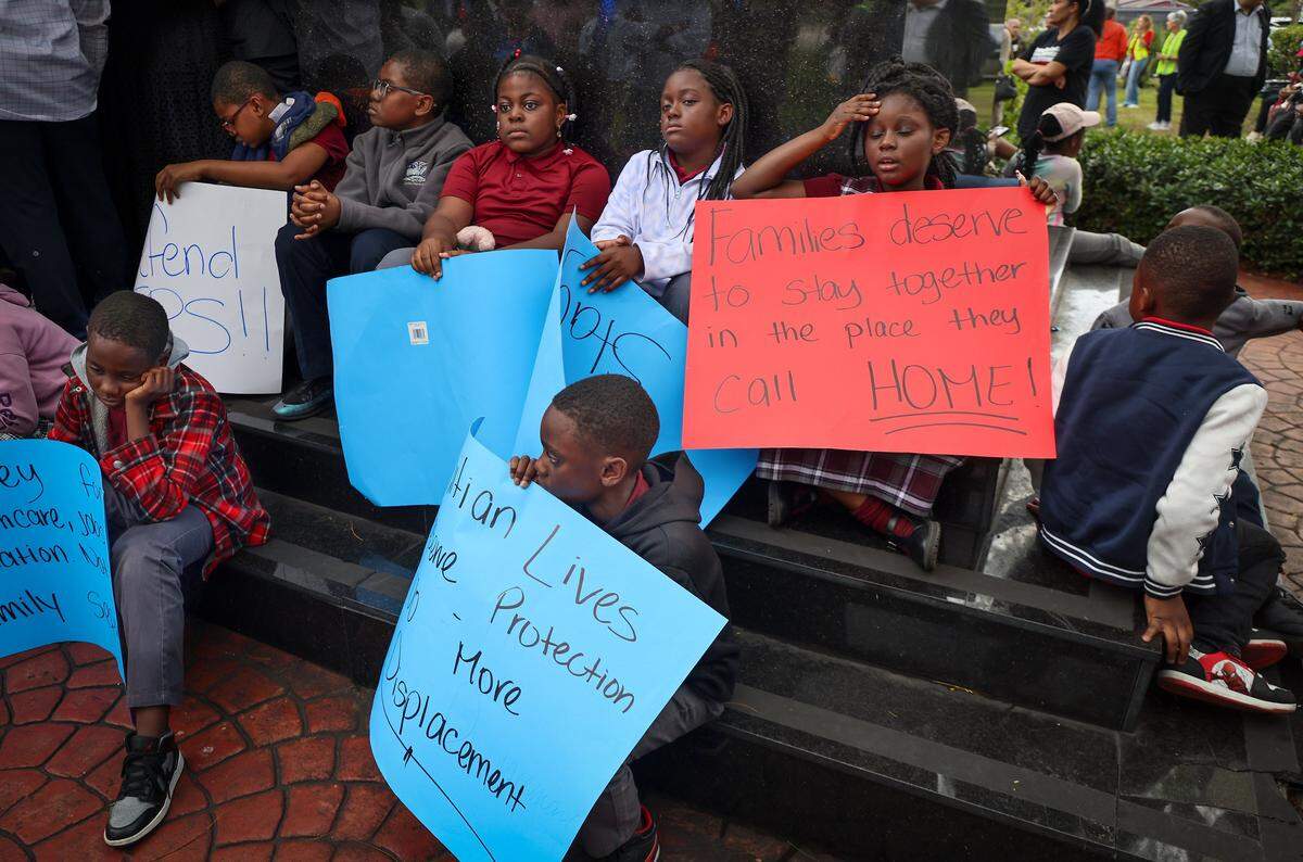 Children bearing signs in support of TPS for Haitians sit at on the steps of the Toussaint Louverture Memorial Statue as they wait for the start for the procession to the Little Haiti Cultural Complex. FANM ( Family Action Network Movement) hosted a community vigil on Monday, Jan. 12, to mark the 16th anniversary of Haiti's devastating 2010 earthquake with a moment of silence at 4:53 pm in remembrance of those who lost their lives and in support of continued TPS for Haitians at the Toussaint Louverture Memorial Statue where featured remarks from community leaders, local politicians, impacted parties and advocates gathered prior to the procession to the Little Haiti Cultural Complex on Monday, January 12, 2026, in Miami, Florida.