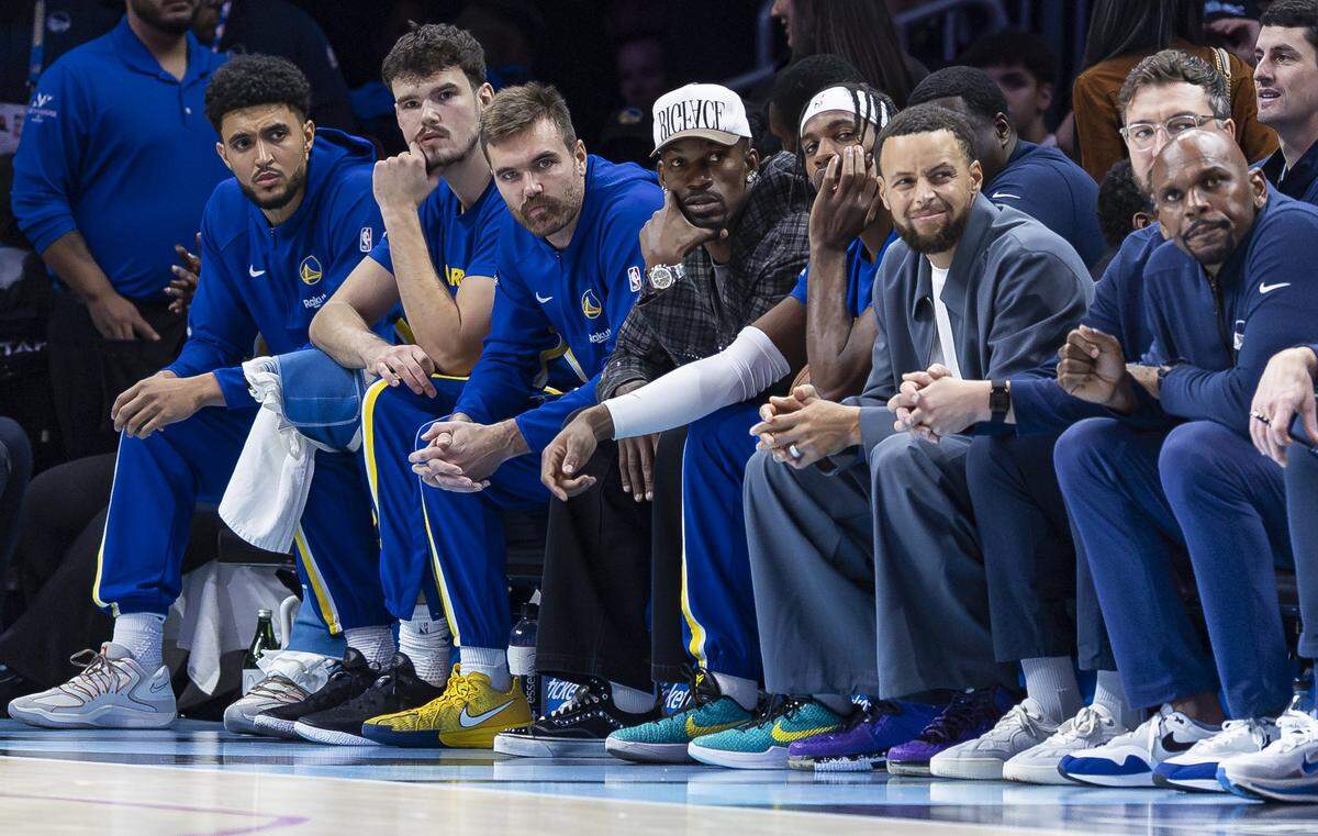 Golden State Warriors guard Stephen Curry (30) and forward Jimmy Butler III (10) watch their team play against the Miami Heat in the first half of their NBA game at Kaseya Center on Nov. 19, 2025, in Miami.