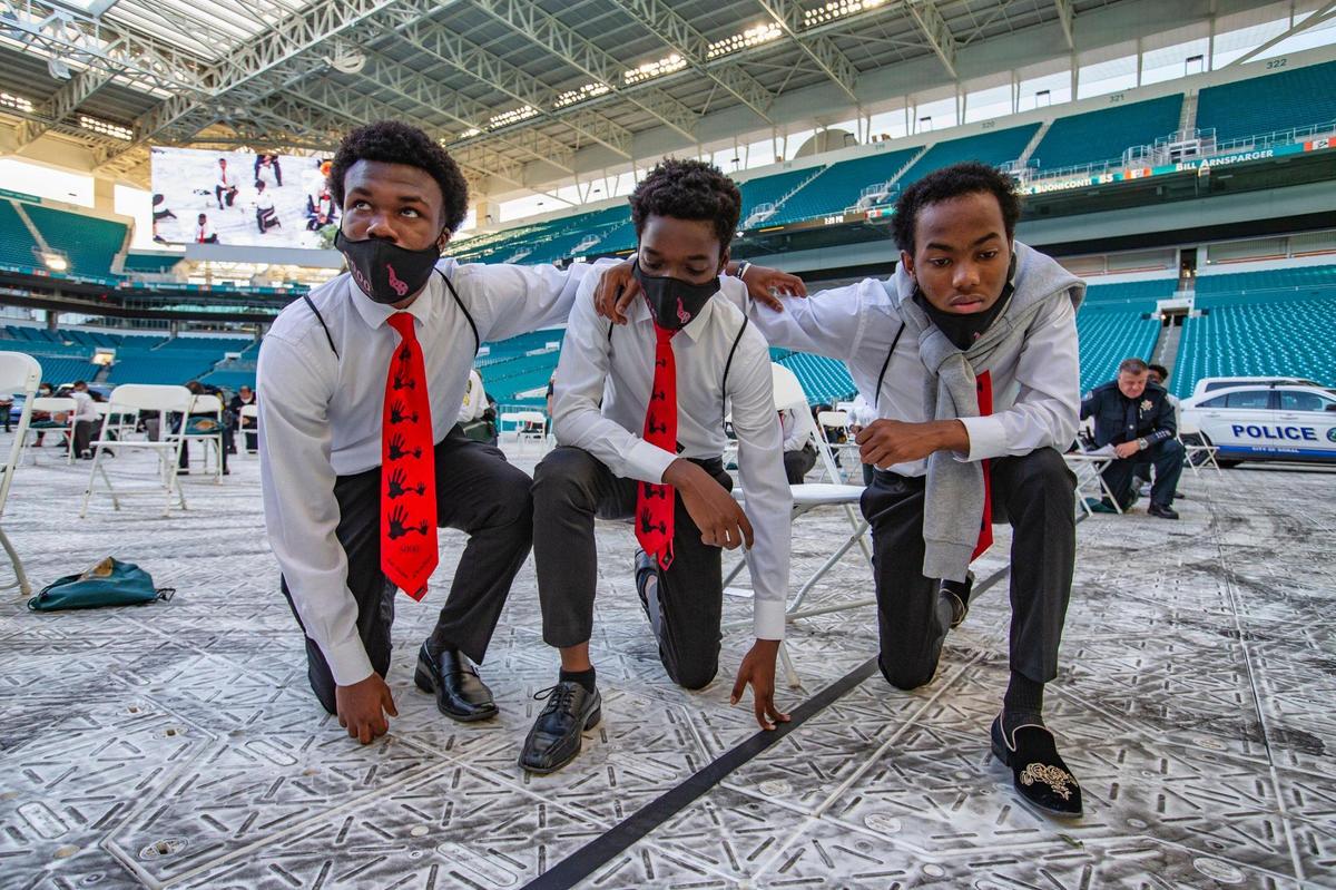 Ashsteve George, 16, Dontes Metelus, 18, and Jean Deniro, 16, of North Miami Senior High School, take a knee during the 5000 Role Models of Excellence Project’s 27th Annual Police & Youth Conference at Hard Rock Stadium on Thursday, June 11, 2020.