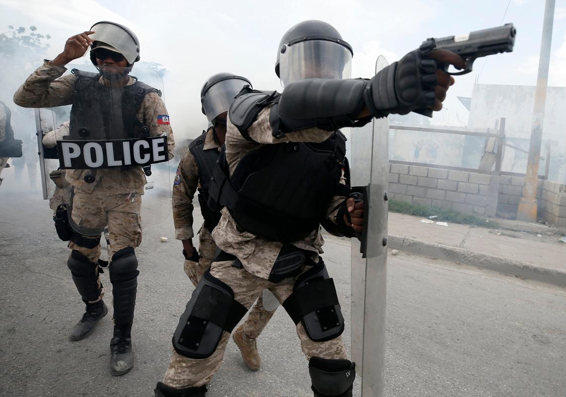 A police officer aims his weapon after demonstrators calling for the resignation of President Jovenel Moise broke through their lines, in Port-au-Prince, Haiti, Friday, Oct. 4, 2019.