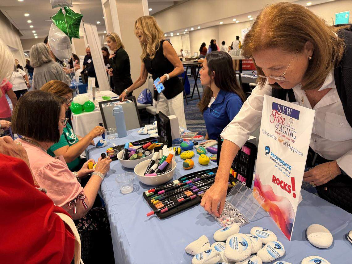 La gente se reúne para colorear rocas inspiradoras como parte de un stand de Providence Healthcare en el evento “El nuevo rostro del envejecimiento: el envejecimiento y el arte de la felicidad”, organizado por la Alianza para el Envejecimiento en Miami, Florida, en mayo de 2025.