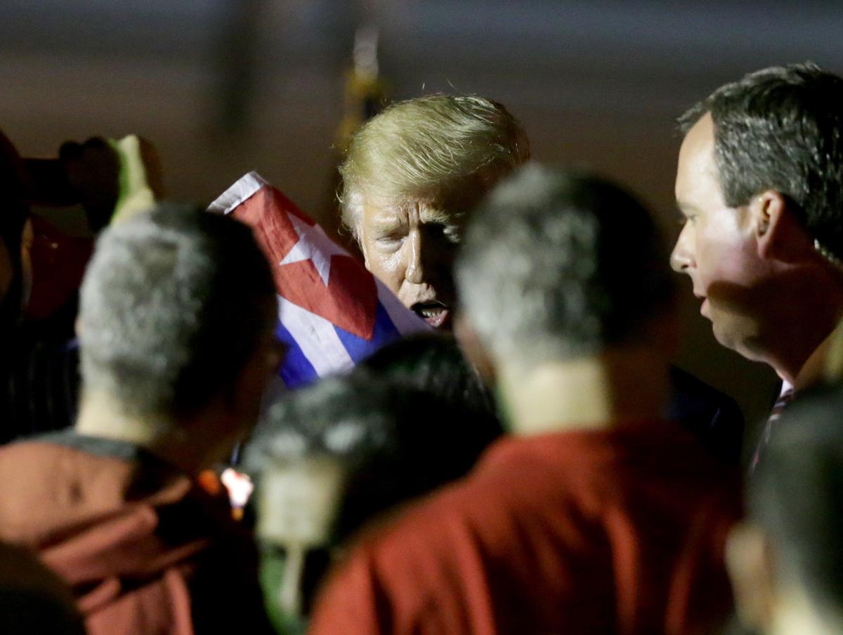 El presidente Donald Trump sostiene una bandera cubana mientras comparte con partidarios a su llegada con la primera dama Melania Trump al Aeropuerto Internacional de Miami, después de lanzar su campaña oificial de reelección en Orlando, Florida.