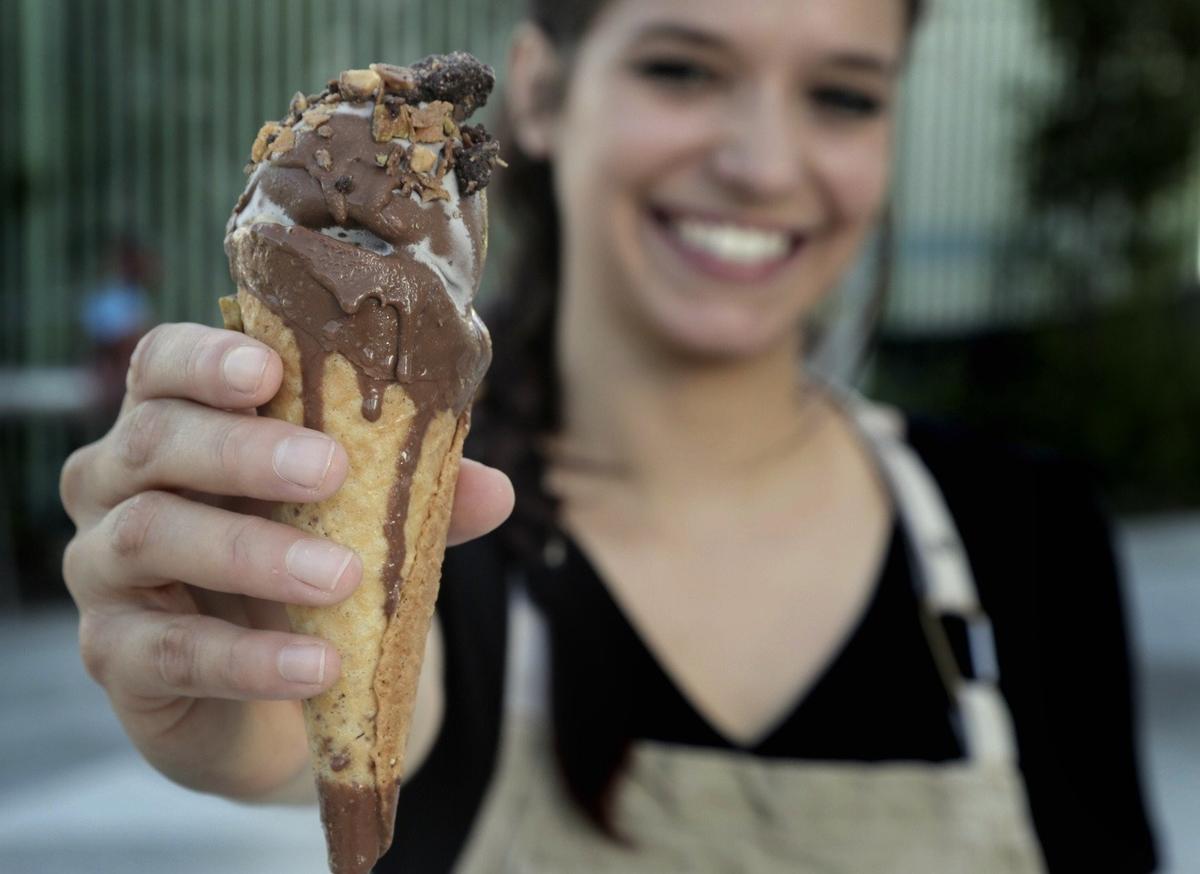 Devin Braddock holds up her version of Drumstick: brown butter waffle cone, rosemary ice cream, pistachios, Valrhona dulcet chocolate. It’s one of the reimagined treats she makes for Tricycle Ice Cream.