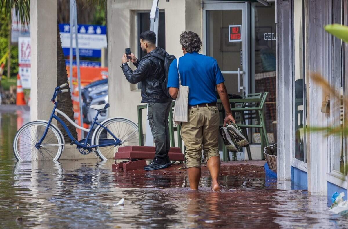 A man walks barefoot on the flooded sidewalks of 71st Street during King Tide in Miami Beach Florida, on Tuesday October 27, 2026.