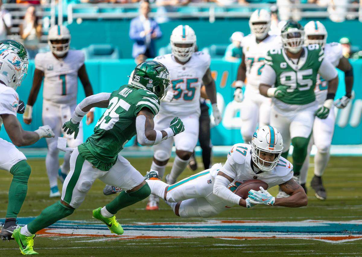 Miami Dolphins wide receiver Jaylen Waddle (17) dives for a first down while New York Jets safety Jalen Mills (35) defends during the first half of their NFL game at Hard Rock Stadium on Sunday, Dec. 8, 2024, in Miami Gardens, Florida.