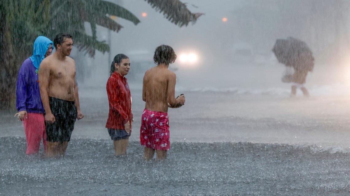 People attempt to cross a flooded street North Beach in Miami Beach, Florida on Wednesday, June 12, 2024.
