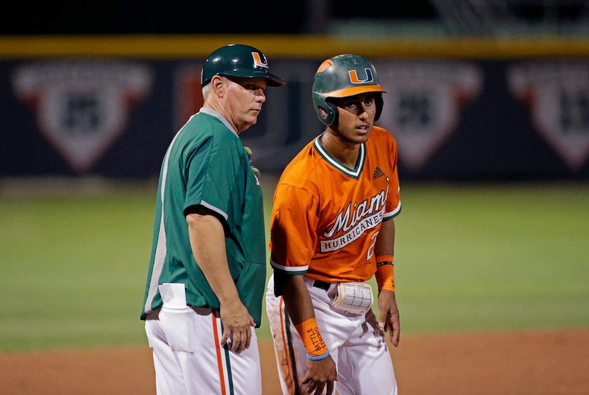 Miami Hurricanes shortstop Anthony Vilar (27) talks with head coach Gino DiMare (6) during the Kent State game at Alex Rodriguez Park at Mark Light Field on Wednesday, February 19, 2020 in Coral Gables.
