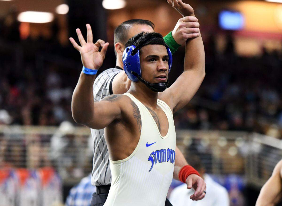 South Dade senior Elvis Solis holds up three fingers after winning his third state title, this time at 144 pounds, on Saturday at the FHSAA IBT wrestling state championships at Silver Spurs Arena in Kissimmee.