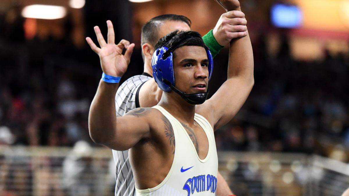 South Dade senior Elvis Solis holds up three fingers after winning his third state title, this time at 144 pounds, on Saturday at the FHSAA IBT wrestling state championships at Silver Spurs Arena in Kissimmee.