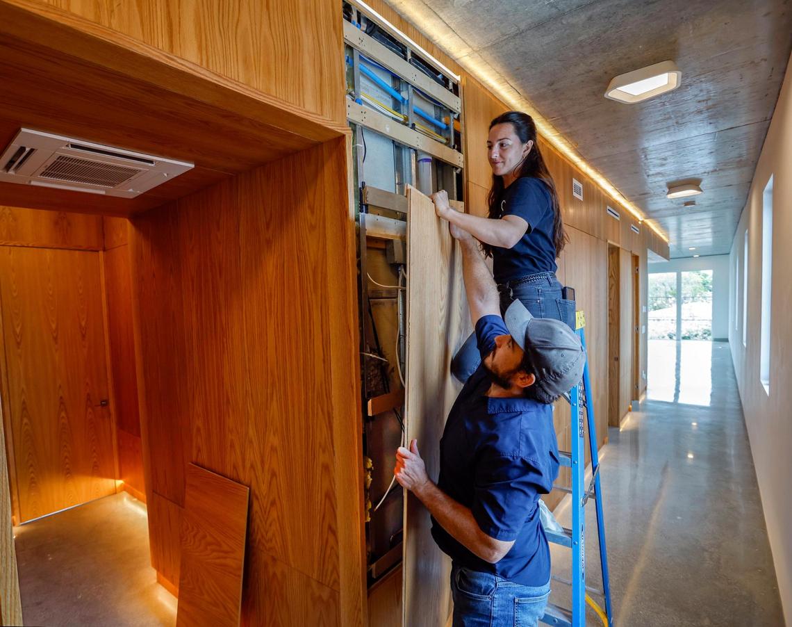 Katie Flood, design associate and construction manager Pedro Alberni, remove an interior panel to access hidden electrical systems on Thursday, April 4, 2024. The newly constructed house in the Miami neighborhood of Silver Bluff landed one of the highest honors in architectural design. It is the first in the world to become a Well Building Institute-certified house.