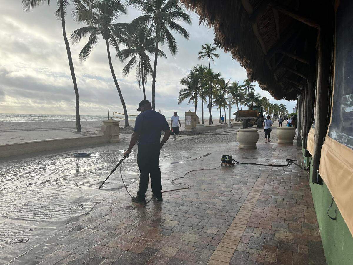Crews clean up sand pushed up onto the Hollywood Broadwalk by Hurricane Nicole on Thursday, Nov. 10, 2022.