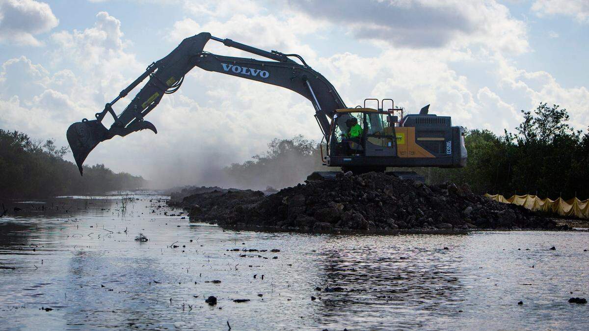 An excavator removes roadbed along Old Tamiami Trail west of Miami on March 30, 2021, as part of the Comprehensive Everglades Restoration Plan to help facilitate water flow back into the Everglades.