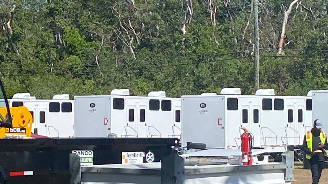 A worker walks past a row of trailers located on a lot on Aregood Lane on Plantation Key in the Florida Keys on Thursday, Feb. 16, 2023. The trailers are part of a state base camp to house police officers sent to the Keys to help with an increase in maritime migration from Cuba and Haiti, according to a statement from the Village of Islamorada.