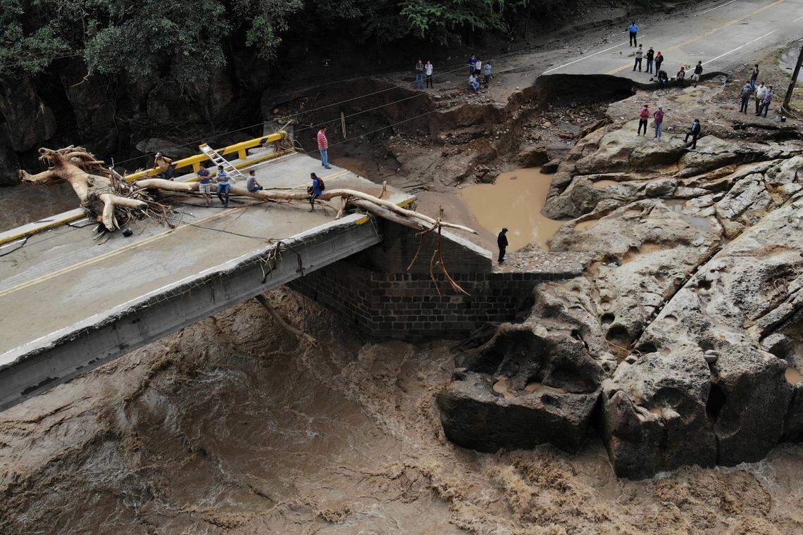 People walk across a destroyed bridge over the Higuito river on November 19, 2020, in Copan, Honduras.