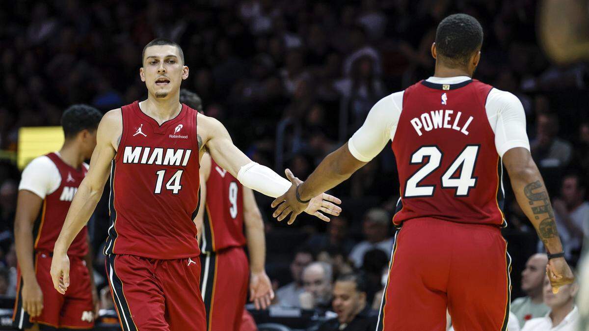 Miami Heat guards Tyler Herro (14) and Norman Powell (24) greet each other on the court during their NBA basketball game against the Milwaukee Bucks at Kaseya Center in Miami on November 26, 2025.
