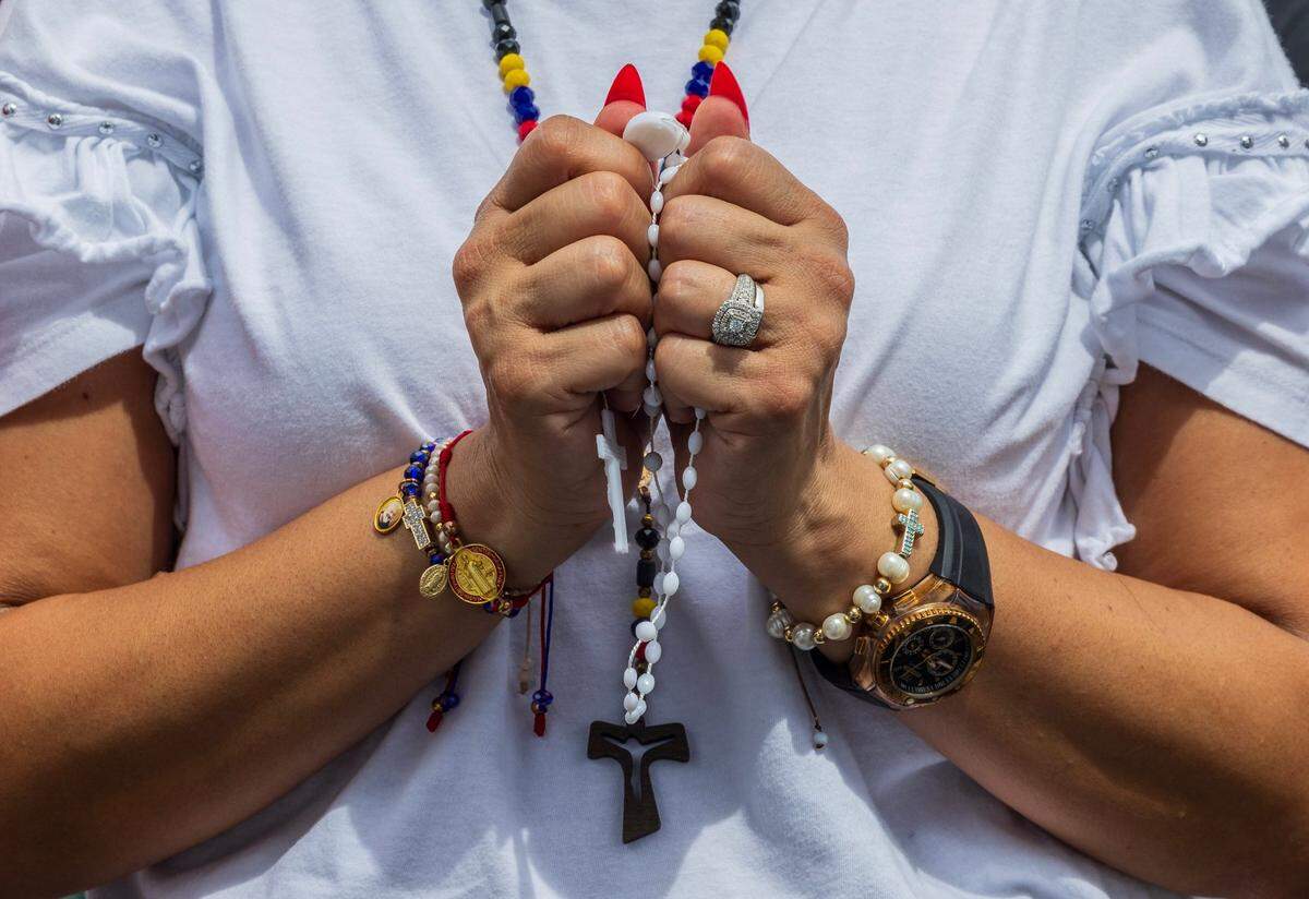 A woman holds a Rosary as she prays during the protest.
