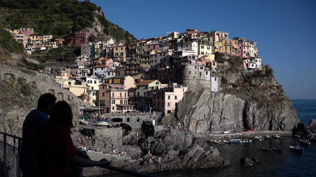 Tourists are silhouetted during the sunset in Manarola in the Cinque Terre National Park, near La Spezia, Nortwestern Italy, on August 13, 2024.