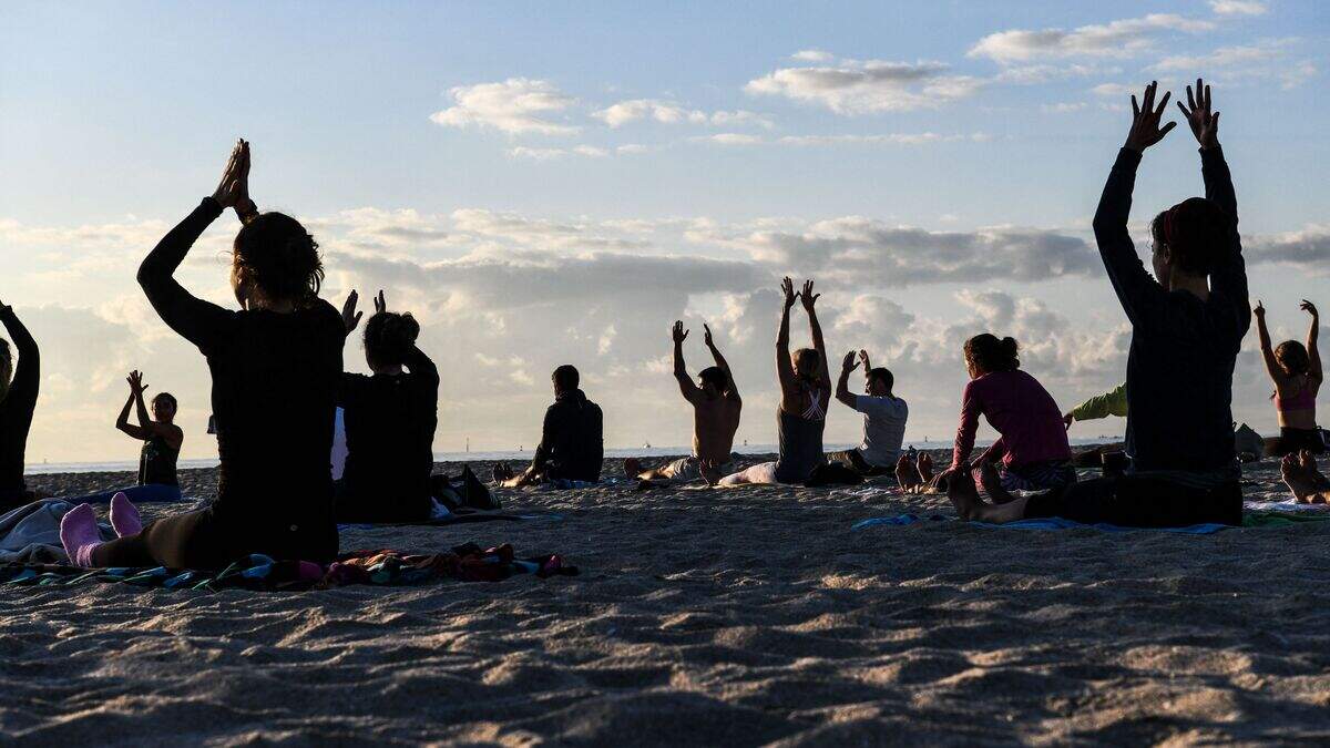 A group of people participate in a yoga session taught by Radha Silva on the beach in Miami Beach, Florida, on March 23, 2021.