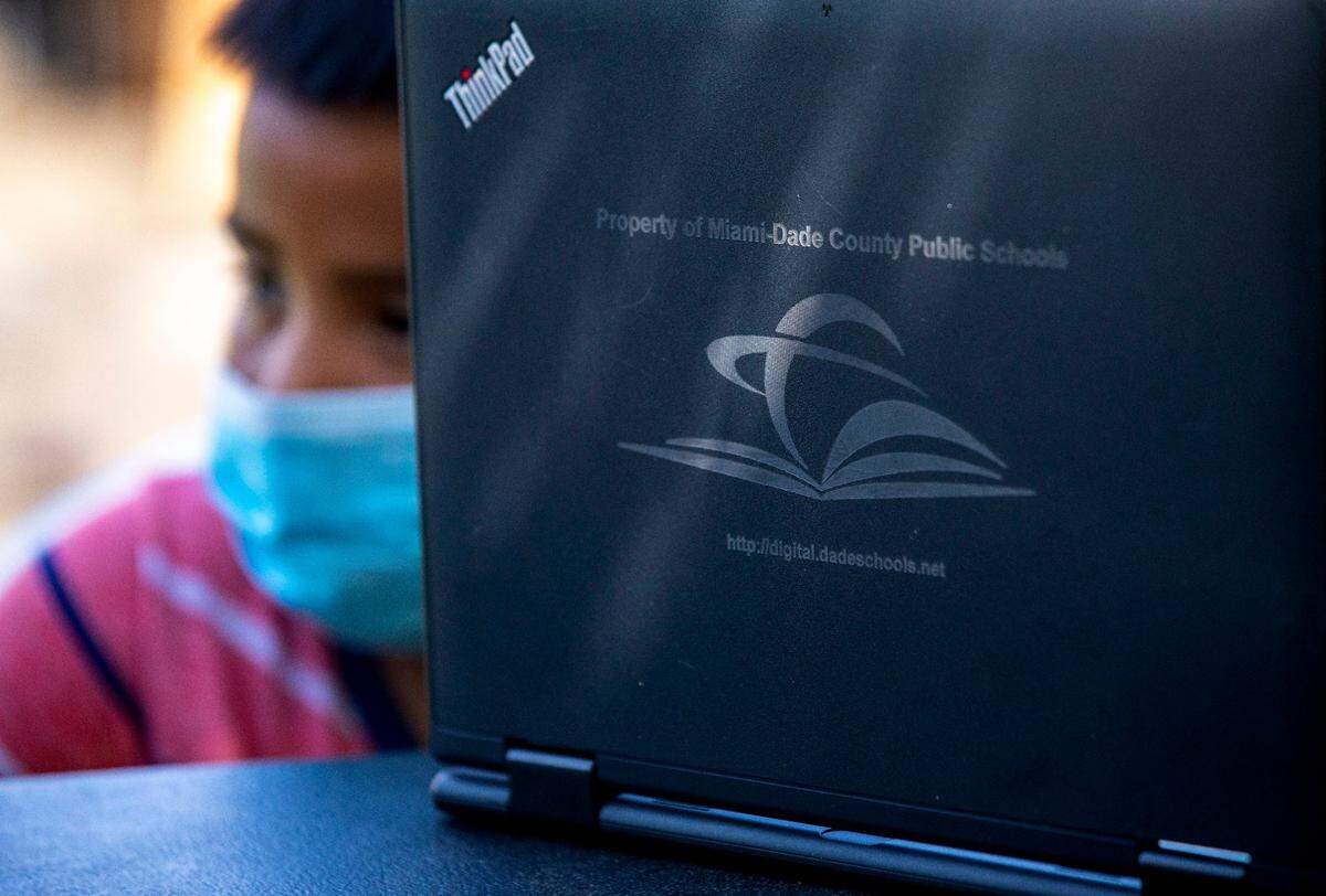 A young migrant boy waits for help with logging on to the student portal from a Miami-Dade County Public Schools employee who had taken a lead role on assisting the kids with virtual learning during the coronavirus pandemic in South Florida on Thursday, May 21, 2020.