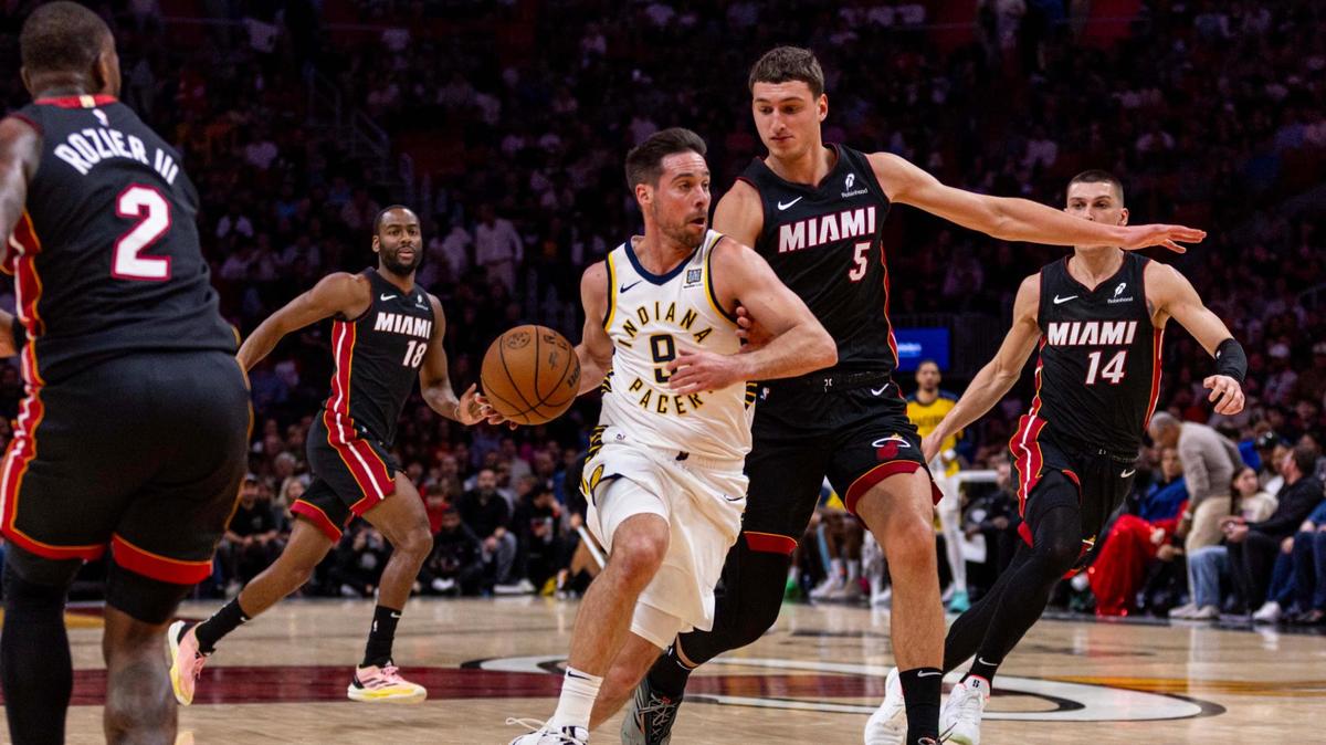 \Indiana Pacers guard T.J. McConnell (9) dribbles into the paint while defended by Miami Heat forward Nikola Jovic (5) during the first half of an NBA game at Kaseya Center on January 2, 2025, in Miami.