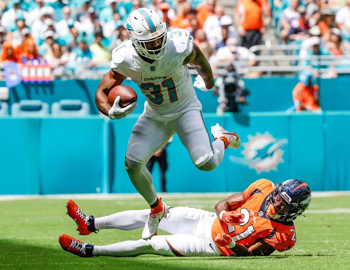 Miami Dolphins running back Raheem Mostert (31) hops over Denver Broncos cornerback Essang Bassey (21) for a first down in the first half at Hard Rock Stadium in Miami Gardens on Sunday, September 24, 2023.