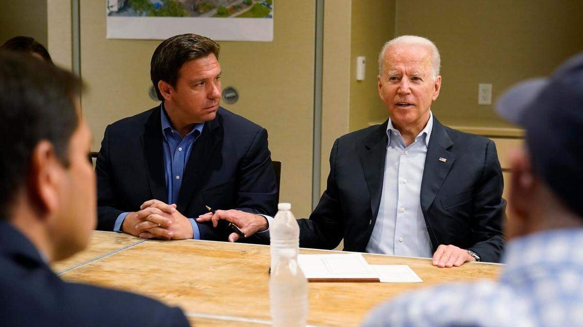 President Joe Biden seen touching Gov. Ron DeSantis’ arm in a meeting after the collapse of Champlain Towers South in Surfside in June 2021. The two will meet again Wednesday in Florida as the president visits after Hurricane Ian.