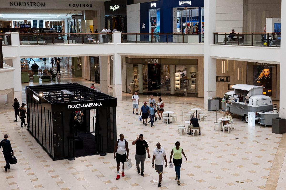 People make their way past a Dolce & Gabbana pop-up shop and Naughty Coffee while visiting Aventura Mall on Wednesday, Sept. 25, 2024, in Aventura, Fla.