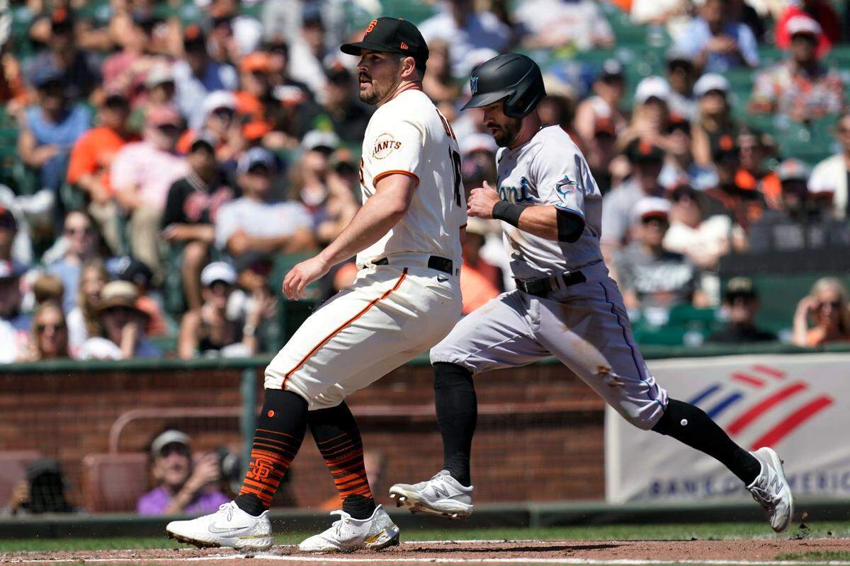 Miami Marlins’ Jon Berti, right, runs home to score on a wild pitch by San Francisco Giants pitcher Carlos Rodon, left, during the third inning of a baseball game in San Francisco, Saturday, April 9, 2022.