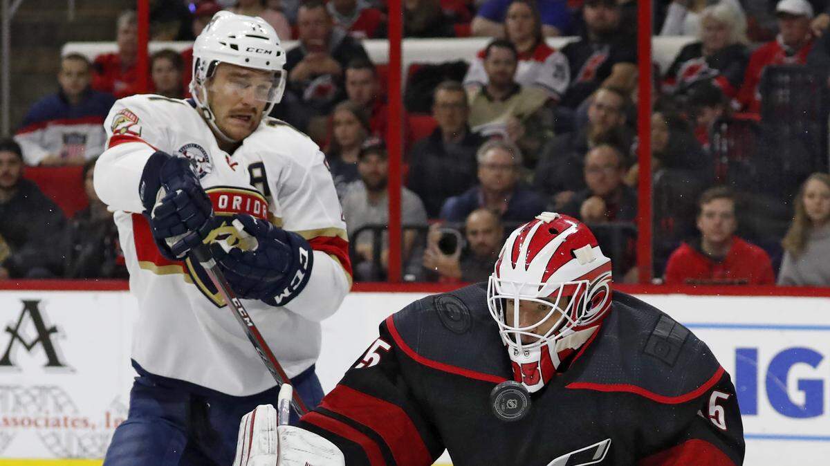 Carolina Hurricanes goaltender Curtis McElhinney (35) blocks a shot as Florida Panthers’ Jonathan Huberdeau (11) waits for the rebound during the first period of an NHL hockey game, Friday, Nov. 23, 2018, in Raleigh, N.C.