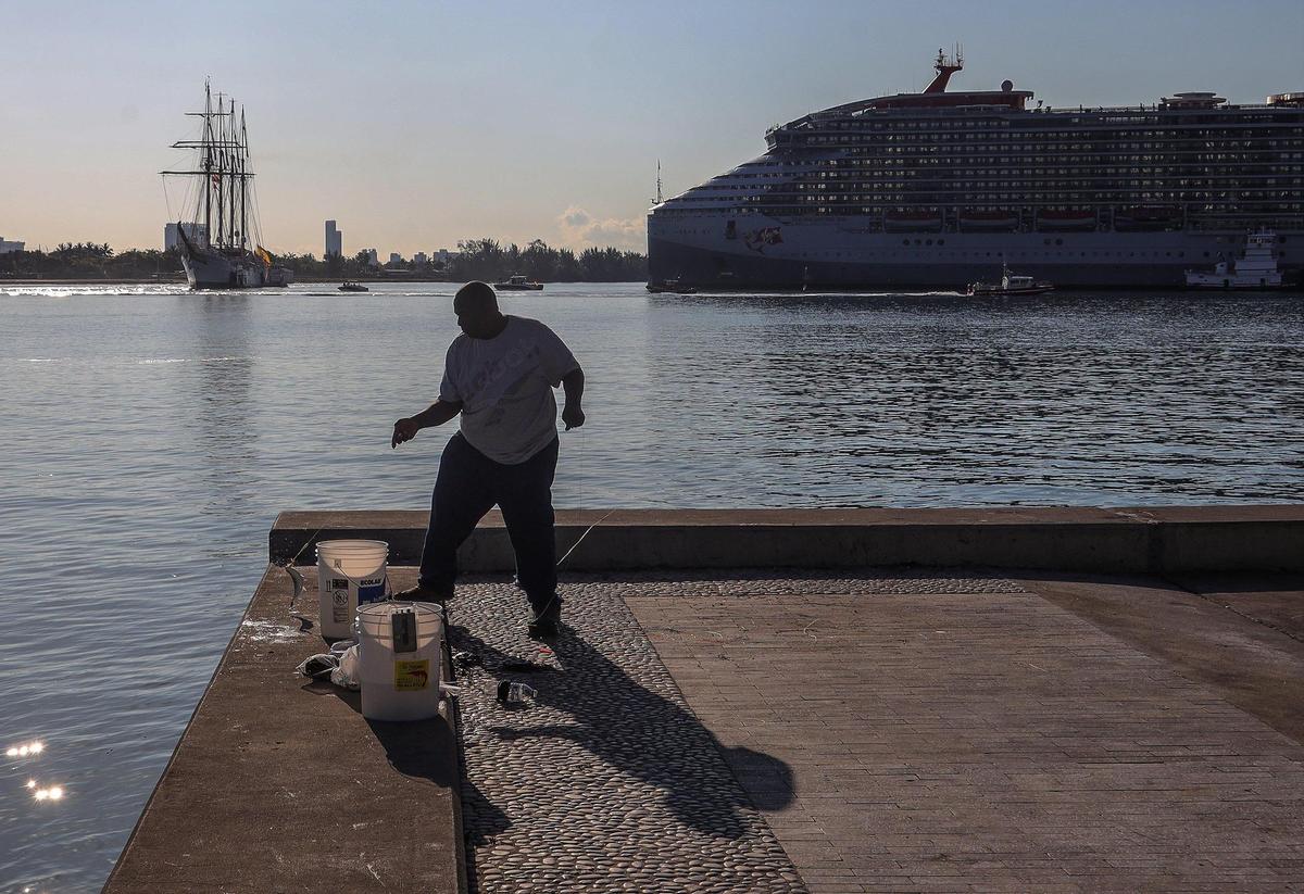 Honduran national Freddie Medina, 61, casts for fish and crabs as the Juan Sebastián de Elcano is piloted into the channel of Maurice A. Ferré Park in downtown Miami, Florida.