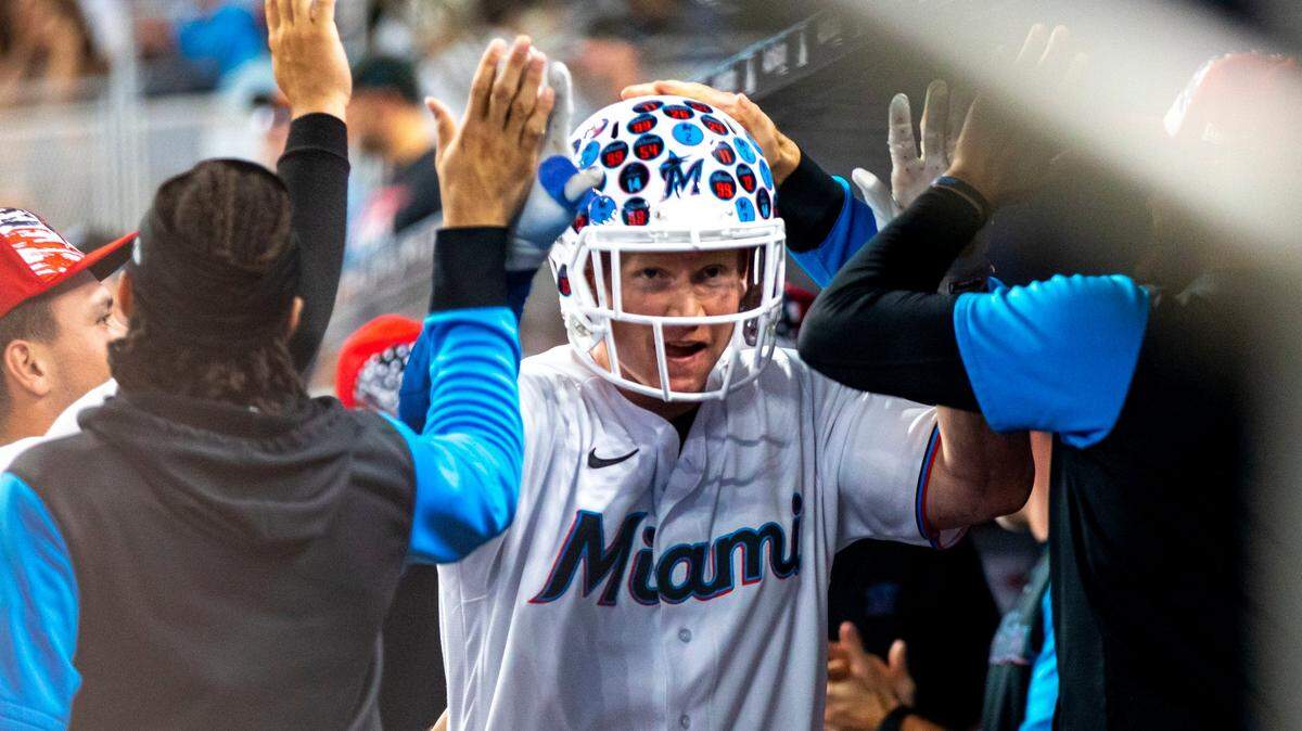 Miami Marlins base runner Garrett Cooper (26) reacts with teammates inside the dugout after homering to center field during the third inning of an MLB game against the Los Angeles Angels at loanDepot park in the Little Havana neighborhood of Miami, Florida, on Tuesday, July 5, 2022.