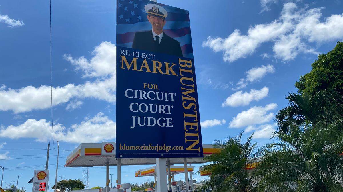 Un cartel de campaña de 2022 del juez del circuito de Miami-Dade Mark Blumstein, un abogado retirado de la Marina de Estados Unidos. En el cartel aparece con su gorra de la Marina.