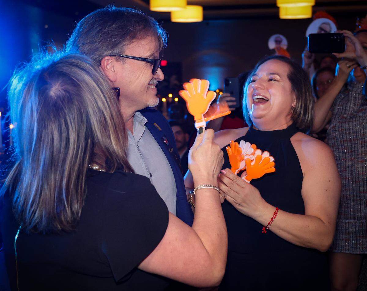 Roberto Rabelo, center,  a social studies and civics teacher at South Miami Middle School, gets a hug from his wife, Patty Rabelo, left, and a smile from his sister-in-law, Monica, as he was named the 2027 Francisco R. Walker Teacher of the Year while taking the stage at the DoubleTree by Hilton Hotel Miami Airport & Convention Center, he received a brand new Toyota Corolla, a cash prize and a gift basket on Wednesday, January 28, 2026, in Miami, Florida. 