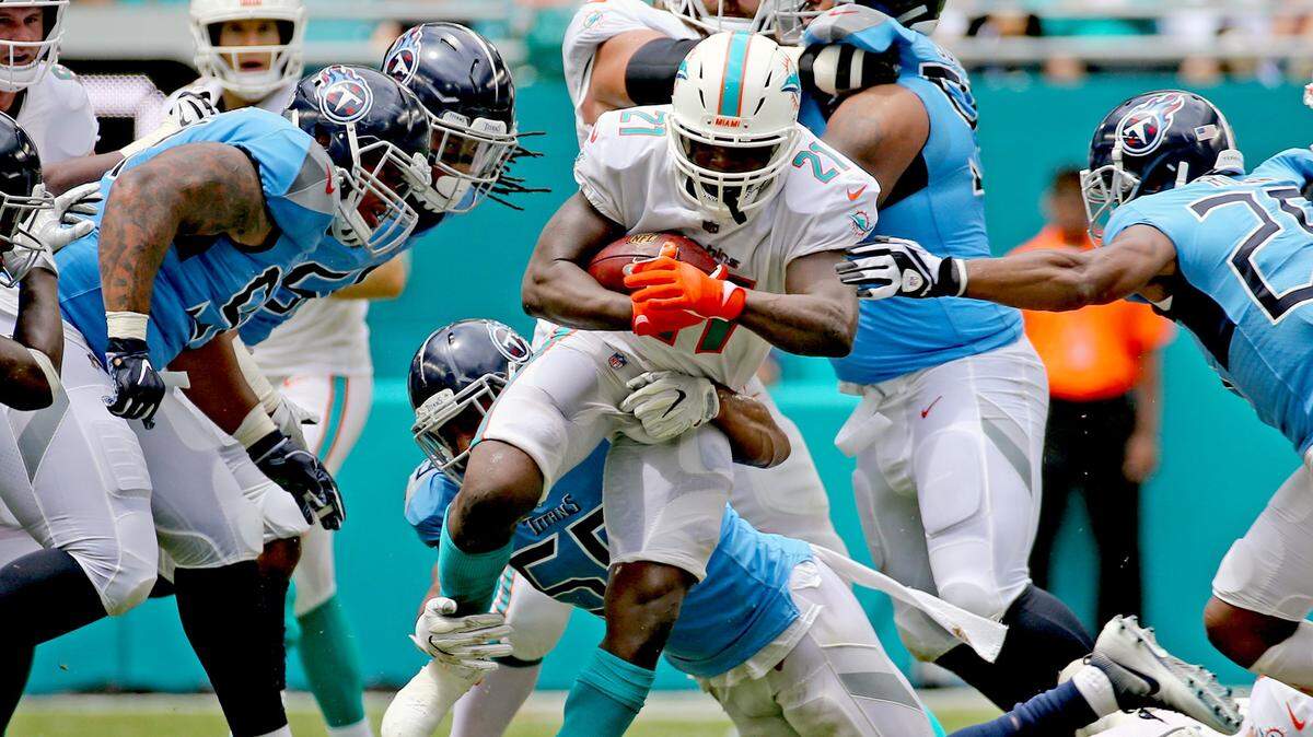 Miami Dolphins Frank Gore (21) runs up the middle as Tennessee Titans Wesley Woodyard (59) attempts to tackle him in the second quarter at Hard Rock Stadium, Miami Gardens, Florida, Sunday, September, 9, 2018.
