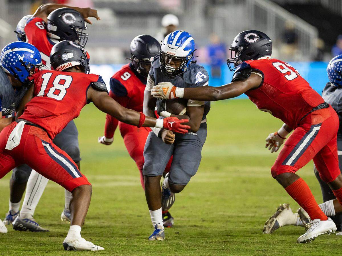 Apopka Blue Darters quarterback Kaleb Hicks (17) tries to run past Columbus Explorers defensive end Dylan Stephenson (18) and defensive tackle Robert Williams (93) during the first quarter of their 2022 FHSAA State Championships-Class 4M football game on Saturday, Dec. 17, 2022, in Fort Lauderdale, Fla.