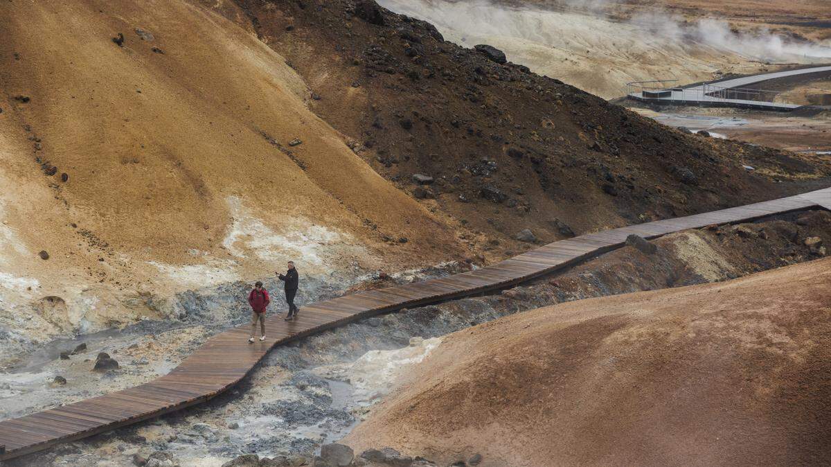 : People walk through a geo thermal area 30km from the town of Grindavik on December 21, 2025 in Grindavik, Iceland.