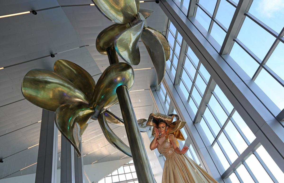 Wendy Gonzalez, dressed all in gold, performs as a â€˜giant greeterâ€™ in front of the â€˜Artistic Kinetic Propeller,â€™ during the grand opening celebration of Royal Caribbeanâ€™s new terminal at Port Miami. Royal Caribbean Cruises Ltd. in a partnership with Miami-Dade County Port Miami is opening a new cruise terminal for Royal Caribbean in Terminal A that will serve as homeport to several Royal Caribbean International ships, including two of the worldâ€™s largest cruise ships â€“ Allure of the Seas and Symphony of the Seas.