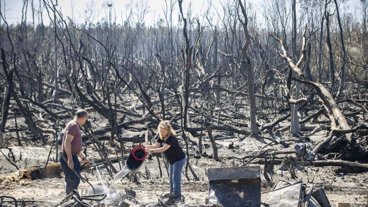 In March, Hector Rivera and Wandi Blanco pour water on hotspots behind their home in Panama City, following a wildfire that destroyed two homes next to them and melted the siding off of their home.
