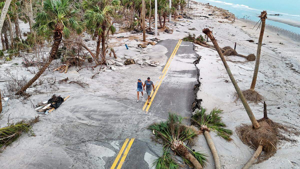 Anna and Alex Marchuk, left to right, walk along a washed out Manasota Key Road on Friday, October 11, 2024. The extensive damage was caused by hurricanes Helene and Milton in Manasota Key, Florida,